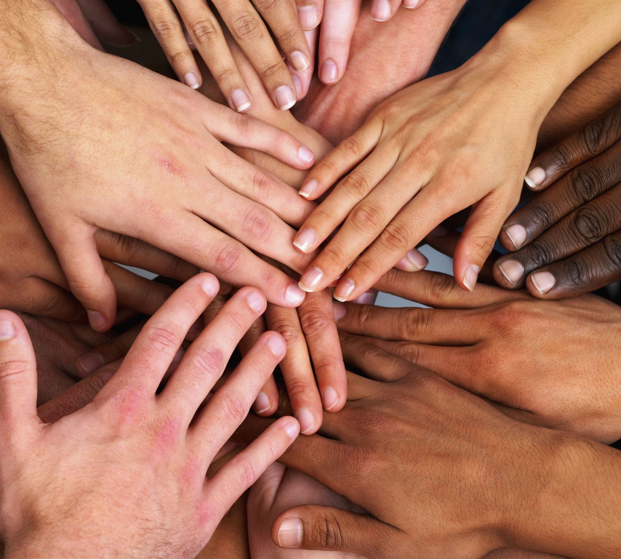 Close-up-of-several-hands-with-palms-facing-down-pointing-towards-center,-overlapping